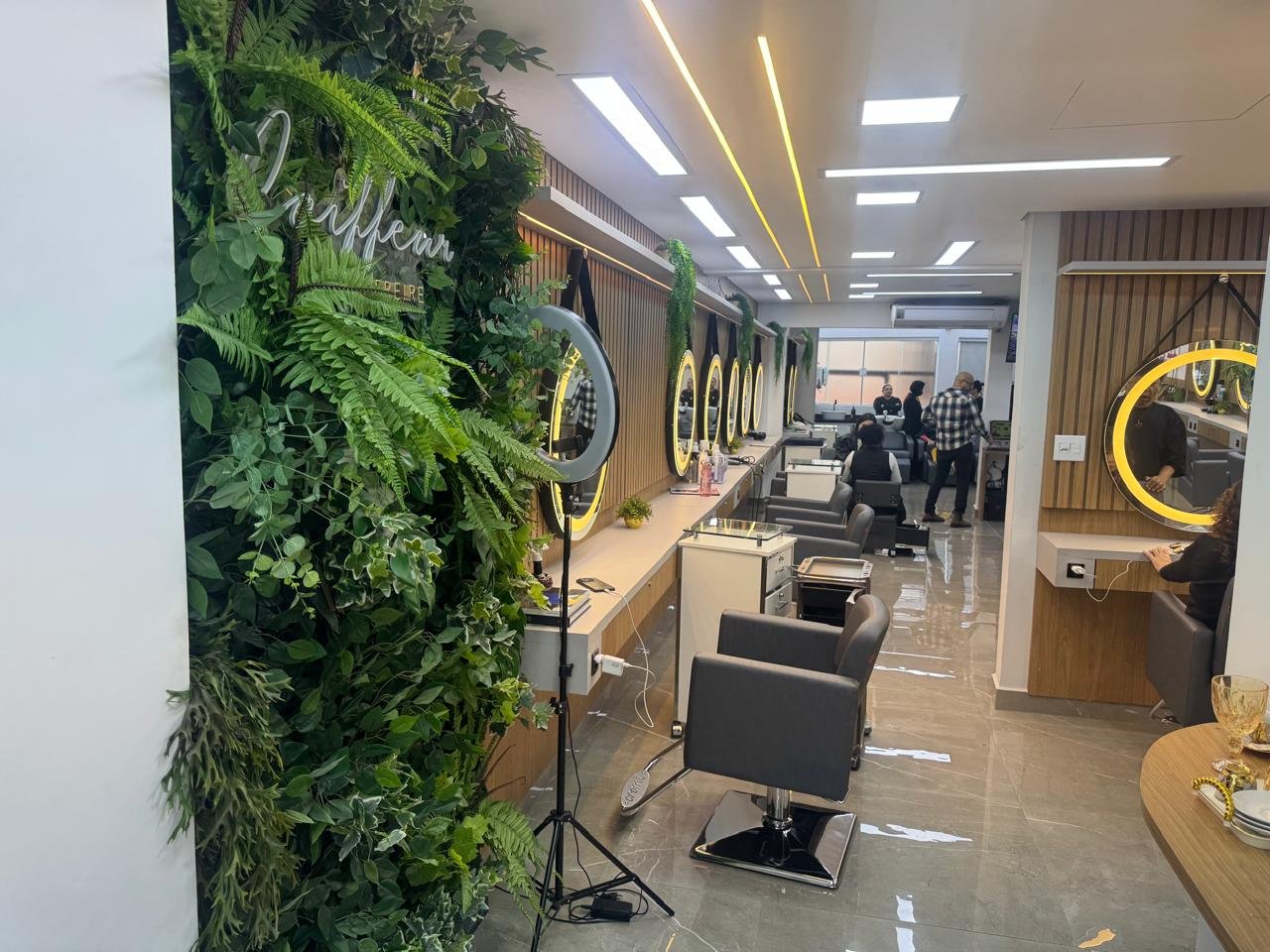 Interior do Coiffeur Oscar Freire com jardim vertical, letreiro neon e estações de atendimento